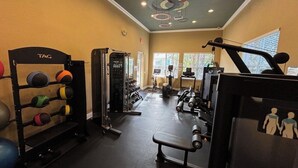 Een sportschool met trainingsapparatuur, een rek vol medicine balls en een bank.