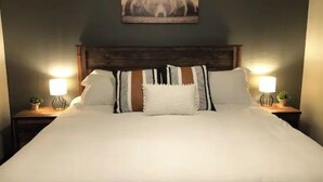 A neatly made bed with white linens and multiple pillows, flanked by two bedside tables with lamps and small potted plants. - Furnished Acreage by Mahoney - Sleeps 17!  Fire Pit - Shuffleboard - Clean! (Ashland)