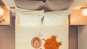 A neatly arranged bed with pillows, a hat, and a piece of clothing on the bed.