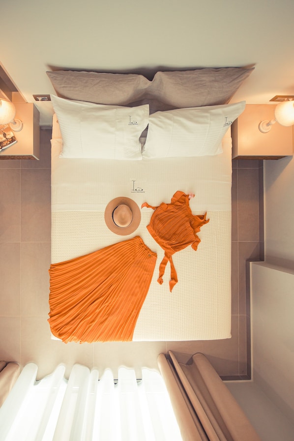 A neatly arranged bed with pillows, a hat, and a piece of clothing on the bed. - IO Luxury Pool & Hot Tub Suites (Preveza)