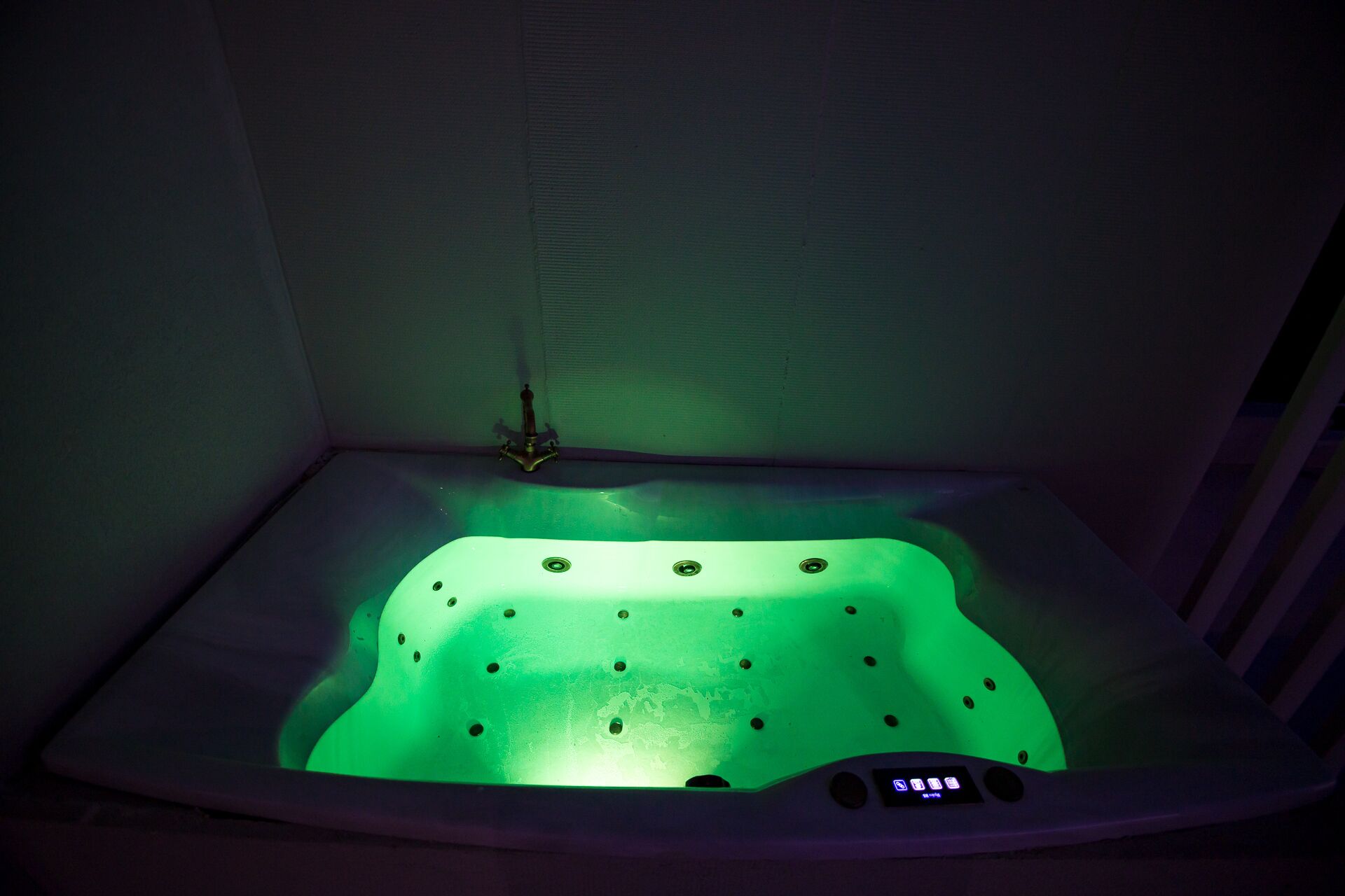 A small, square-shaped hot tub with a digital control panel and a single faucet.