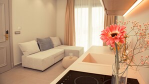 A modern living room with a sofa, a coffee table, and a vase with flowers.