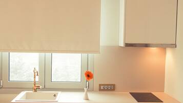 Una cocina moderna con armarios blancos, horno empotrado y ventana sobre el fregadero.