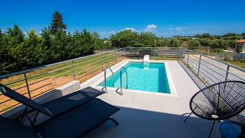 A rooftop pool with a clear view of the surrounding landscape, including trees and distant buildings.