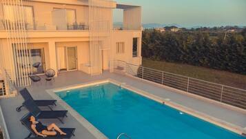 Un edificio moderno de dos pisos con zona de piscina en la azotea.