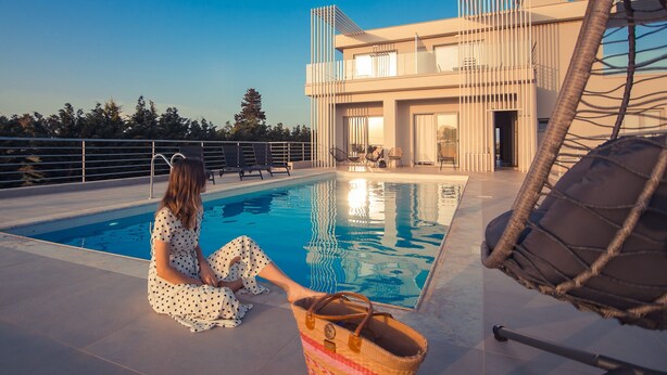 A modern poolside area with a clear view of the pool, lounge chairs, and a building with large windows.