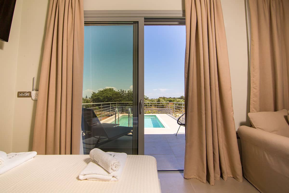 Een hotelkamer met een bed, een badkamer en een balkon met zwembad.