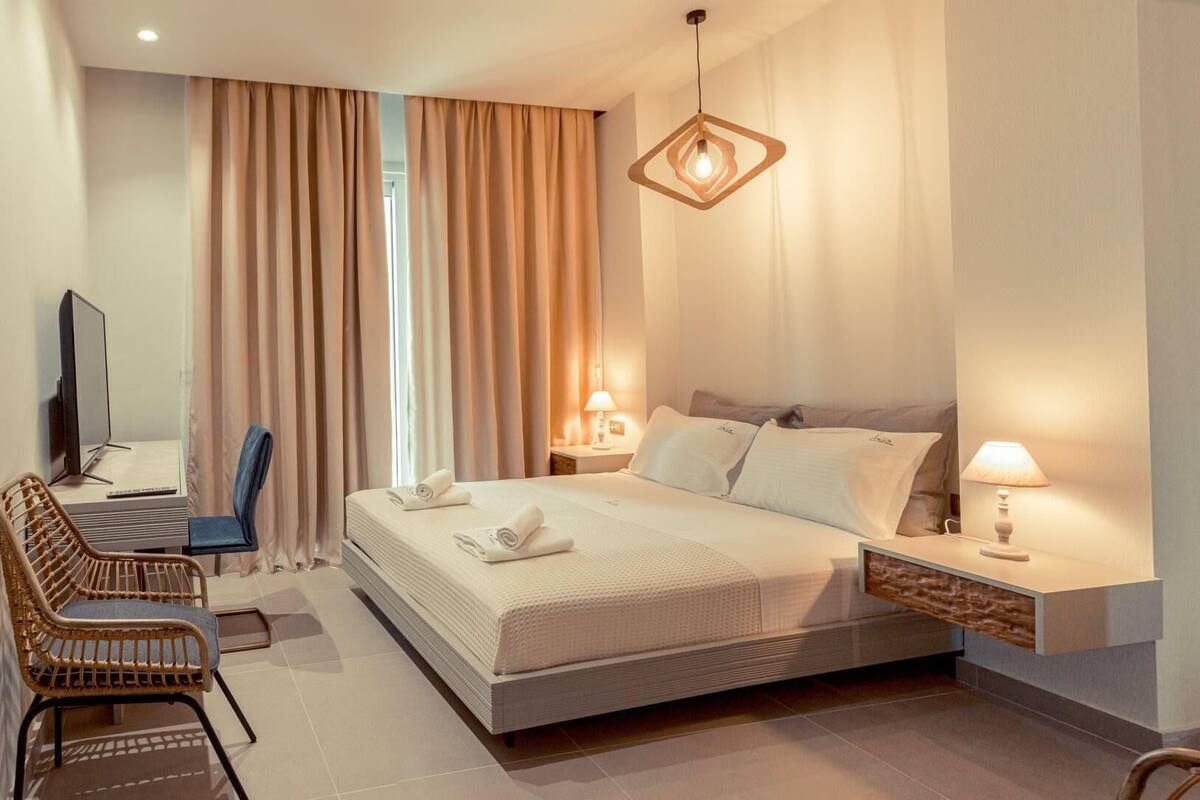 Een moderne hotelkamer met een groot bed, een bureau met stoel, een televisie en een bijzondere hanglamp.