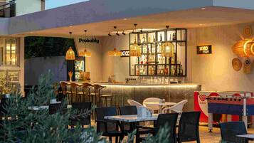 An outdoor bar area with seating, a foosball table, and a bar stocked with bottles.
