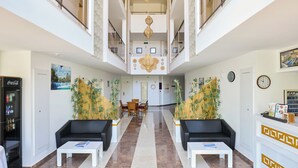 A spacious lobby with a high ceiling, a reception desk, two sofas, a coffee table, and a dining area. - A Hotel Side (Manavgat)