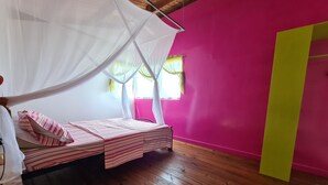Une chambre avec un lit sous un baldaquin blanc, un mur rose et un plancher en bois.
