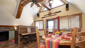 A dining area with wooden tables and chairs, a ceiling fan, and a view of the outdoors through large windows. - Spacious 4BR/4BA Table Rock Lake Retreat (lampe)