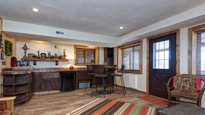 A spacious kitchen with a central island, wooden cabinets, and a built-in stove. There are two bar stools and a dining table with chairs. - Spacious 4BR/4BA Table Rock Lake Retreat (lampe)
