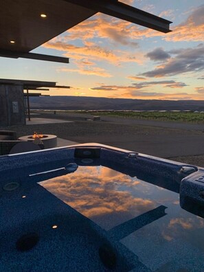 Ein Whirlpool mit Blick auf einen Sonnenuntergang über einem Weinberg.