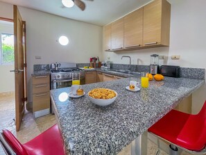 Una cocina con encimeras de granito, estufa a gas, lavamanos y armarios de madera.