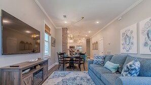 Ein modernes Wohnzimmer mit einem blauen Teppich mit Muster, einem grauen Sofa mit dekorativen Kissen und einer Holz-Unterhaltungseinheit mit einem Fernseher.