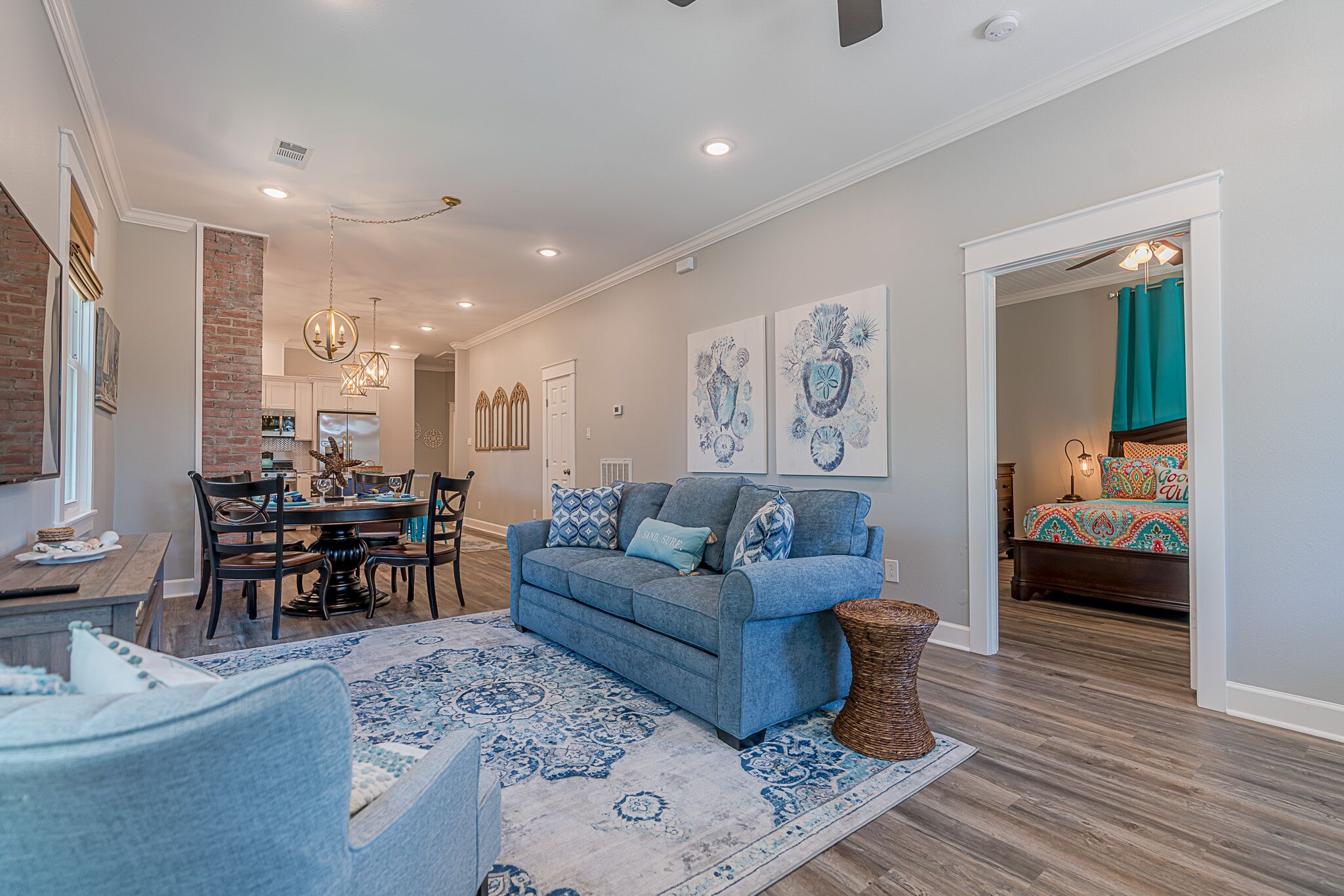 A spacious living room with a blue sofa, a dining area with a wooden table, and a kitchen in the background.