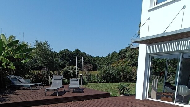 Uma piscina moderna ao ar livre, com deck de madeira e espreguiçadeiras.