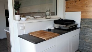 Cozinha moderna com uma ilha grande, fogão embutido e parede de destaque em pedra.