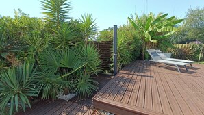 Um deck de madeira com uma espreguiçadeira branca e uma pérgula de metal.