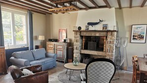Ein gemütliches Wohnzimmer mit Kamin, einer Couch, einem Esstisch und einem Sessel.