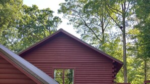 A red wooden cabin with a garage and a covered vehicle. - Log Cabin/Cottage on Watts Bar Lake (Ten Mile)