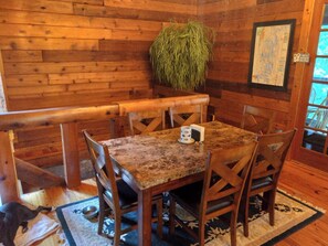 A wooden interior with a dining table, chairs, a potted plant, and a map on the wall. - Log Cabin/Cottage on Watts Bar Lake (Ten Mile)