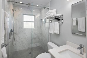 Une salle de bain moderne avec une douche à parois de verre, des toilettes et un lavabo avec un miroir.