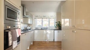Uma cozinha moderna com eletrodomésticos de aço inoxidável, armários brancos e piso de madeira.