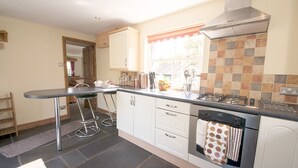 A kitchen with a gas stove, oven, and a window with a view of the outdoors. - Family-sized Lake District village house with garden, plus gorgeous walks from the door (Coniston)