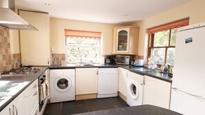 A compact kitchen with a gas stove, microwave, toaster, and a dishwasher. - Family-sized Lake District village house with garden, plus gorgeous walks from the door (Coniston)