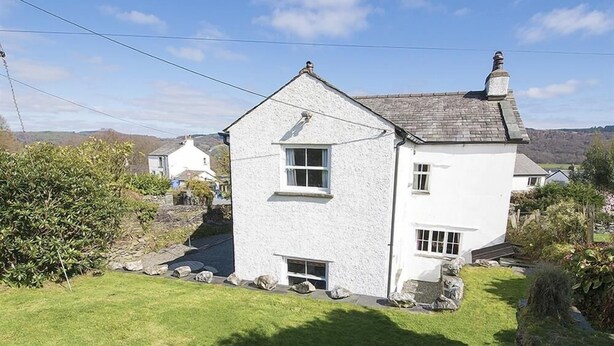 A white two-story house with a sloped roof, a chimney, and a small front porch. - Family-sized Lake District village house with garden, plus gorgeous walks from the door (Coniston)