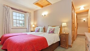 Une chambre double avec deux lits, des têtes de lit en bois, des lampes de chevet, une fenêtre avec des rideaux et un plafond en bois.