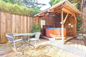 Relax in a serene hot tub surrounded by lush greenery and a wooden pergola.