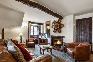 Cozy living room with a fireplace, leather sofa, and armchairs, perfect for relaxing.