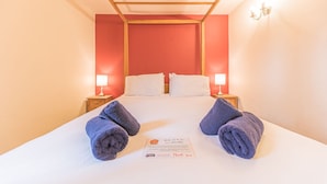Une chambre d’hôtel avec un lit, deux tables de chevet et un mot sur le lit.