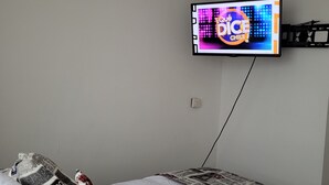 A bedroom with a bed covered in newspaper, a television on the wall, and a white ceiling light. - EXELENTE VISTA AL MAR Y MUY CERCANOS A PLAYAS, CENTRO DE LA CIUDAD. (Valparaíso)