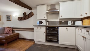 A kitchen with white cabinets, a built-in oven, a microwave, and a kettle on the countertop. - Unique mountain cottage for 4 with hot tub and stunning views (Coniston)