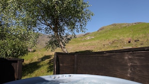 A hot tub with a wooden fence and a tree in the background. - Unique mountain cottage for 4 with hot tub and stunning views (Coniston)