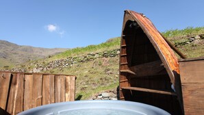 Un bain à remous doté d’une structure en bois et d’un mur de pierre en arrière-plan.