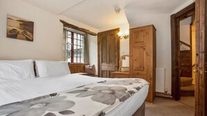 Une chambre à coucher avec un lit, une fenêtre avec des rideaux, une armoire en bois et une porte.