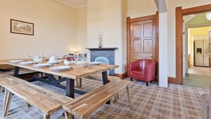 A dining area with wooden tables and benches, a fireplace, and a red chair. - Large Lake District House in popular village with gorgeous lake views (Coniston)