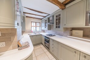 A kitchen with light-colored cabinets, a stainless steel refrigerator, a built-in oven, and a gas stove.