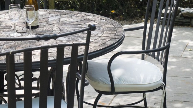 A round table with a bottle of wine and glasses, surrounded by metal chairs with cushions. A sign reads "Top Garden Suite." - Lake District cottage with gorgeous views in Beatrix Potter country (Ambleside)