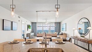 A modern kitchen with granite countertops, stainless steel sink, and pendant lighting.