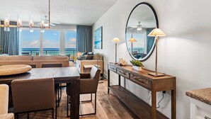 A modern living room with a wooden dining table, leather sofas, and a large mirror.