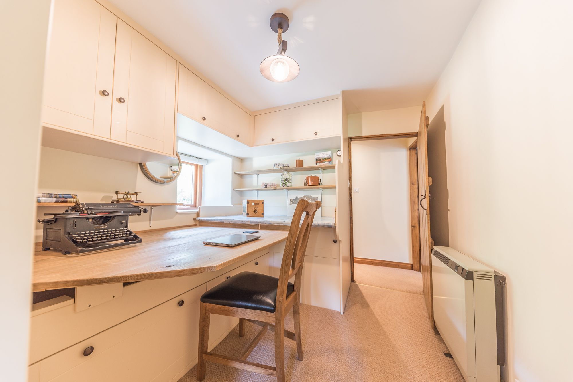 A compact kitchen with a wooden countertop, a vintage typewriter, and a chair.