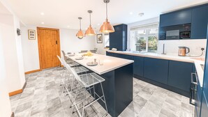 Una cucina moderna con isola centrale, illuminazione a sospensione e vista sull'esterno.