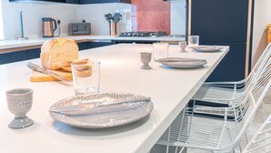 Una cucina moderna con un'isola allungata, piani di lavoro bianchi e un lavello in acciaio inossidabile.
