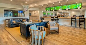 A bar area with multiple screens, a sofa, and wicker chairs.